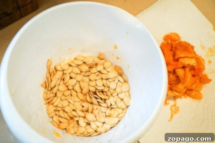 Clean Pumpkin Seeds Effortlessly 4 A spoon scooping out pumpkin seeds and pulp from inside a hollowed-out pumpkin.