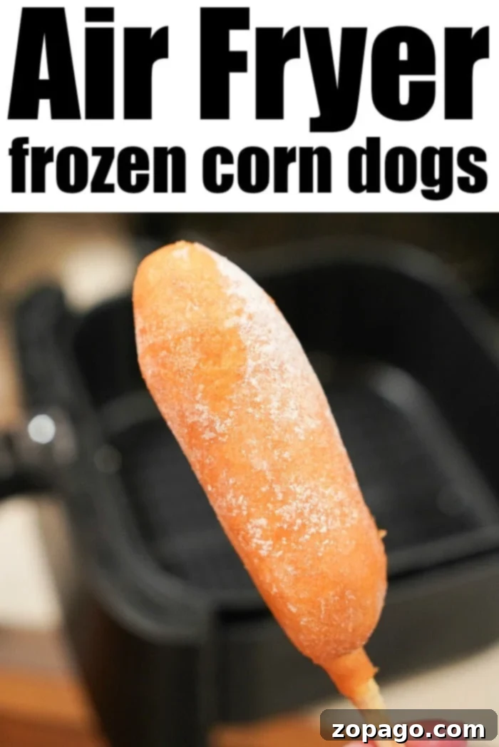 Best Air Fryer Corn Dogs Recipe Close-up of a hand holding a perfectly air-fried frozen corn dog, golden-brown and crispy, with the air fryer in the background.