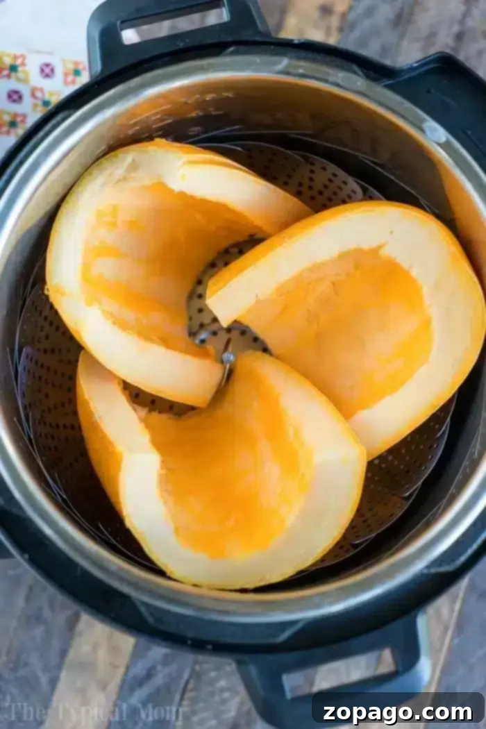 Cozy October Instant Pot Recipes 2 Three pumpkin slices rest inside an Instant Pot with a steamer basket, perfect for October's cozy recipes. Cut into large wedges, they showcase their bright orange flesh. The pot sits invitingly on a wooden surface.
