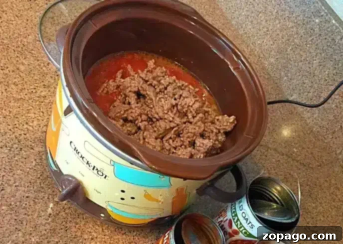 A Crock-Pot filled with browned ground beef and tomato sauce.