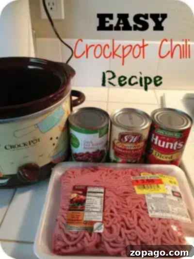 Image of a kitchen counter with ingredients for a 5 ingredient crockpot chili recipe. A crockpot is next to three cans (light red kidney beans, tomato sauce, diced tomatoes) and a package of ground beef.
