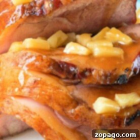 Sliced ham topped with pineapple chunks and glaze creates a festive December dish, beautifully presented on a white plate.