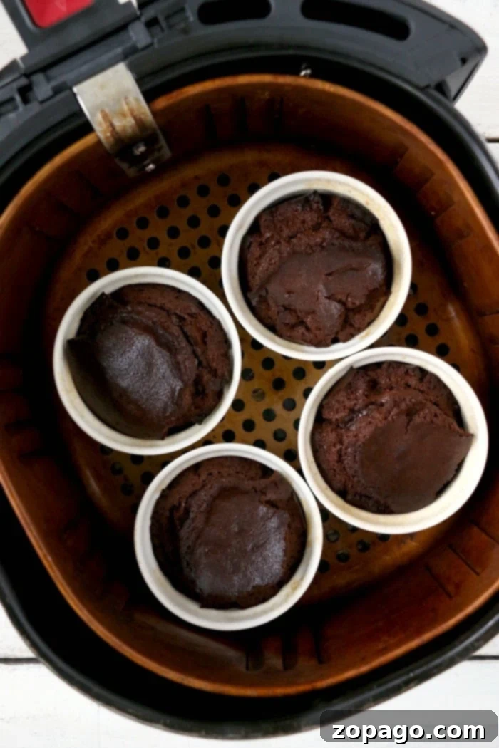 Best air fryer cake will become your new favorite dessert! Ooey gooey chocolate lava cake made in ramekins inside your Ninja Foodi or other brand. #airfryerrecipes #airfryerdessert #airfryercake #chocolatecake #lavacake #ninjafoodirecipes #ninjafoodi #foodi Ninja Foodi cake in ramekins, perfectly baked with a molten center, served with fresh berries.