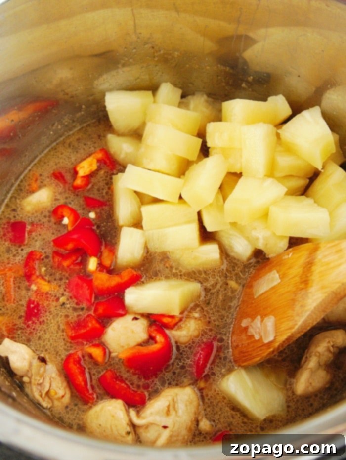 Pressure cooker pineapple chicken is great served on top of rice. Cooked in no time with peppers and sweet fruit your family will love this pressure cooker meal. A serving of Ninja Foodi pineapple chicken in a white bowl