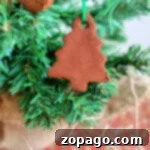A delightful cinnamon ornament, crafted from a cherished recipe, hangs gracefully on an evergreen branch in the shape of a Christmas tree.