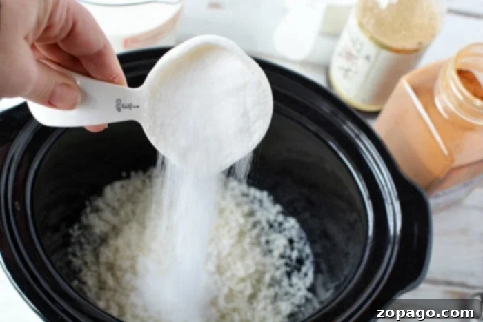 Creamy Slow Cooker Rice Pudding 4 Someone pouring sugar into a slow cooker, preparing to create a creamy rice pudding.