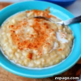 Effortless Slow Cooker Steel Cut Oats 5 A blue bowl of creamy slow cooker steel cut oats is topped with cinnamon and milk, with a spoon resting inside.