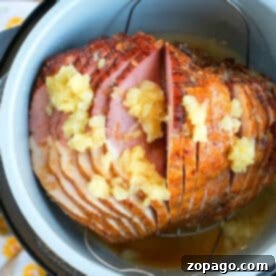 A spiral-cut ham with pineapple chunks and juice in a Ninja Foodi, ready to be cooked to perfection.
