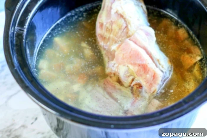 Effortless Slow Cooker Black Eyed Peas 5 A close-up shot of a rich, savory ham bone simmering in a pot, demonstrating a key ingredient for flavorful slow-cooked dishes like black-eyed peas.