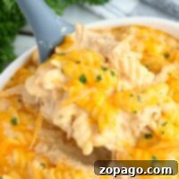 Creamy cheesy chicken rotini pasta, cooked to perfection in an instant pot, garnished with herbs and served from a white bowl.