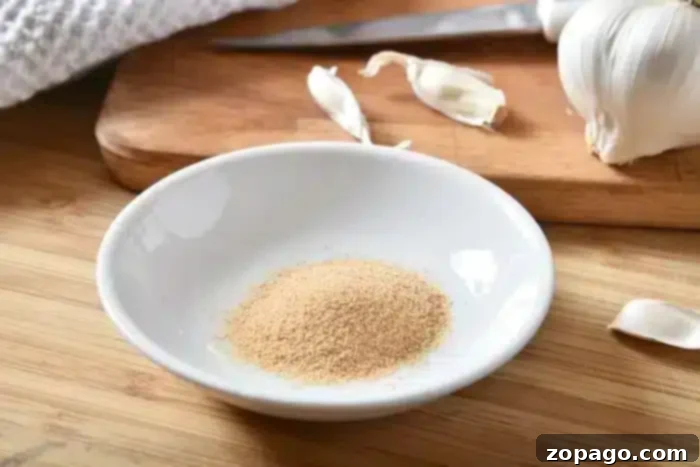 Flavorful Dry Rub Baked Pork Chops 6 A small white dish filled with garlic powder, positioned on a rustic wooden surface, alongside fresh garlic cloves and a cutting board with a knife, highlighting an essential ingredient for the best baked pork chops.