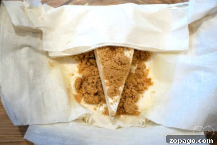 Easy Air Fryer Brie & Crescent Bundles 6 Brie cheese topped with brown sugar, wrapped in parchment paper, becomes irresistible when transformed