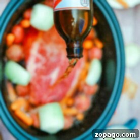 Pouring beer into a crockpot with meat, onions, carrots, and baby potatoes creates a flavorful roast enhanced by the savory touch of onion soup mix.