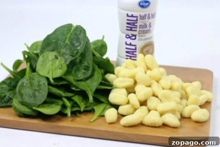 Easy Ninja Foodi Chicken Gnocchi Soup 3 A vibrant bowl of gnocchi soup with a spoon, placed on a blue and white checkered tablecloth.