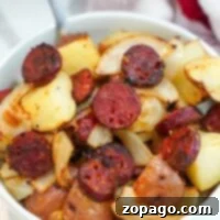 A bowl of air-fried sausage with crispy roasted potatoes and caramelized onions.