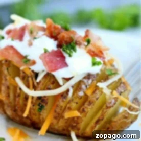 An air fryer Hasselback potato loaded with cheese, crispy bacon, sour cream, and fresh herbs.