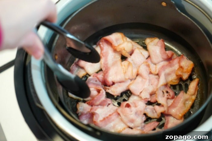 Crispy Air Fryer Bacon 4 Bacon cooking inside a Ninja Foodi air fryer basket.