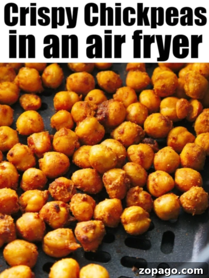 Crispy high protein air fryer chickpeas tossed in taco seasoning for a quick snack on the go. Close-up image of air fryer chickpeas in a basket. The golden brown chickpeas look perfectly seasoned. Text at the top reads "Crispy Chickpeas in an Air Fryer.