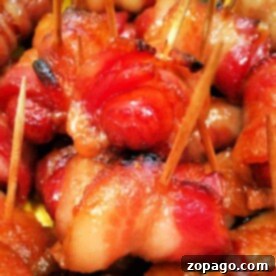 Irresistible Air Fryer Bacon Wrapped Smokies 9 Close-up image of Bacon Wrapped Smokies secured with toothpicks. The bacon is cooked to a crispy, golden-brown finish in the Ninja Foodi. The appetizers are closely packed, showcasing the texture and color variation from the caramelized and well-cooked bacon.