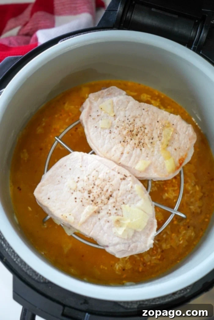Ninja Foodi Pork Chops with Rice 6 Ninja Foodi pork and rice cooking in the pressure cooker, showing the layers of rice and pork on a trivet
