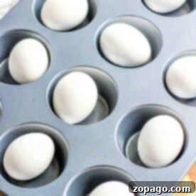 Eggs in a muffin tin on a yellow cloth, ready for the oven—a simple method for how to hard boil eggs in the oven.