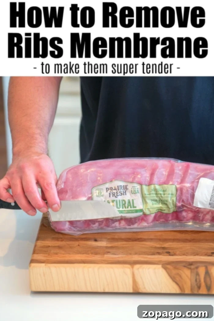 How to remove membrane from ribs so they're super tender. A close-up view of hands carefully removing the thin membrane from the back of a rack of ribs, revealing the tender meat beneath.