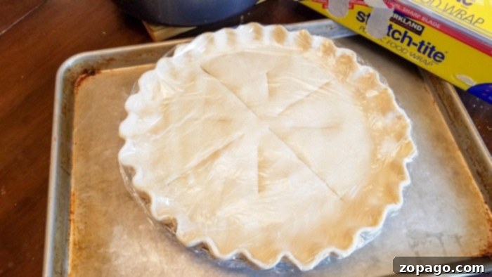 From-Scratch Leftover Turkey Pot Pie 9 Three unbaked turkey pot pies wrapped for freezing, sitting on a baking sheet.