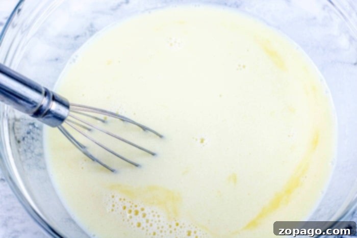 Whip Up Perfect Homemade Waffles 6 Smooth, golden waffle batter being gently whisked in a glass bowl.