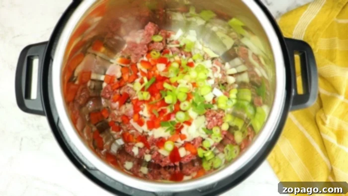 Instant Pot dirty rice ingredients laid out on a wooden board, showcasing raw ground beef, rice, and seasonings.