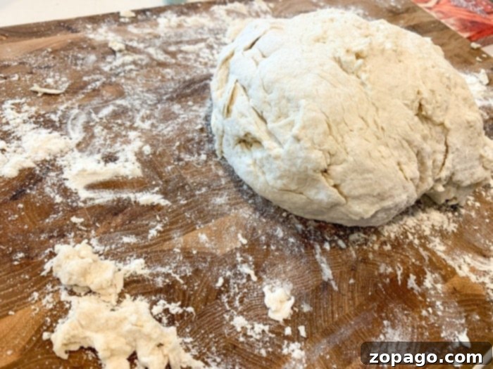 Effortless 3-Ingredient Bread 3 A ball of Irish soda bread dough resting on a lightly floured cutting board, ready for baking.