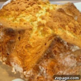 Close-up of freshly baked, golden-brown No Yeast Irish Soda Bread with a cracked crust resting on parchment paper.