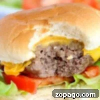 Close-up of a partially eaten cheeseburger with lettuce and tomato, reminiscent of the juicy flavor one might achieve with instant pot hamburgers.