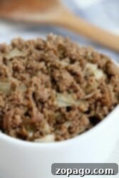 A bowl of succulent crockpot ground beef mixed with chopped onions.