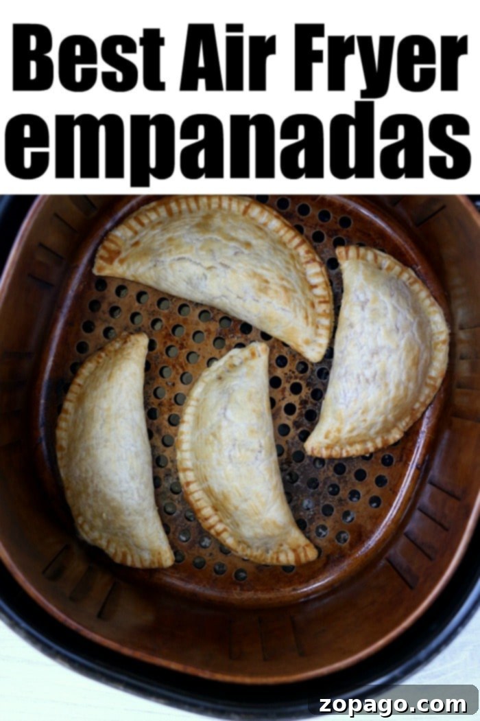 Crispy Air Fryer Empanadas 8 Four golden air fryer empanadas resting in an air fryer basket, perfectly cooked.