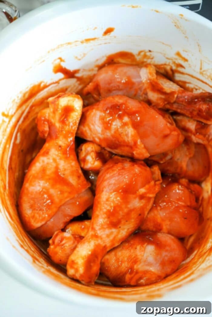 Ultimate Ninja Foodi Barbecue Drumsticks 6 Raw chicken drumsticks coated in a vibrant red marinade, waiting to be cooked in the Ninja Foodi.