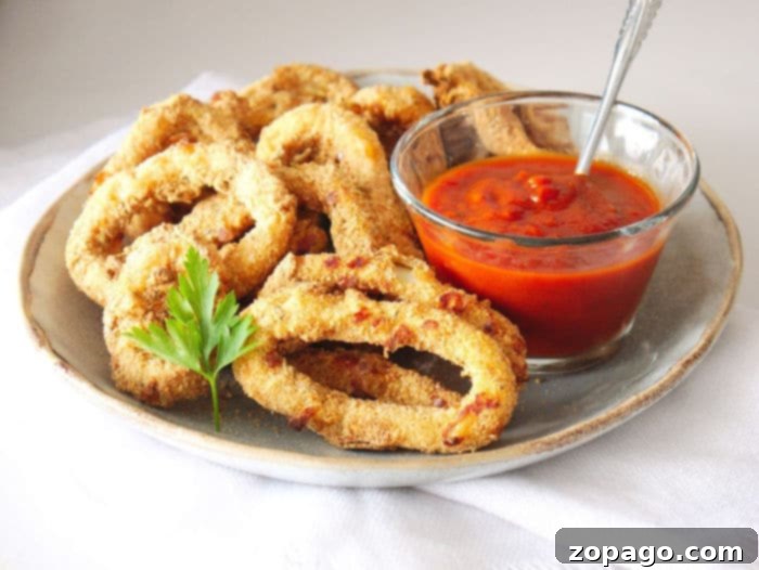 A plate of homemade air fried calamari with lemon and dipping sauce.