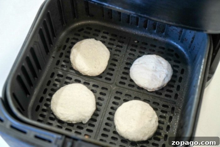 Air Fryer Frozen Biscuits: Golden Perfection 6 Delicious air fryer frozen biscuits with a light golden crust, resting in the air fryer basket, ready to be enjoyed.