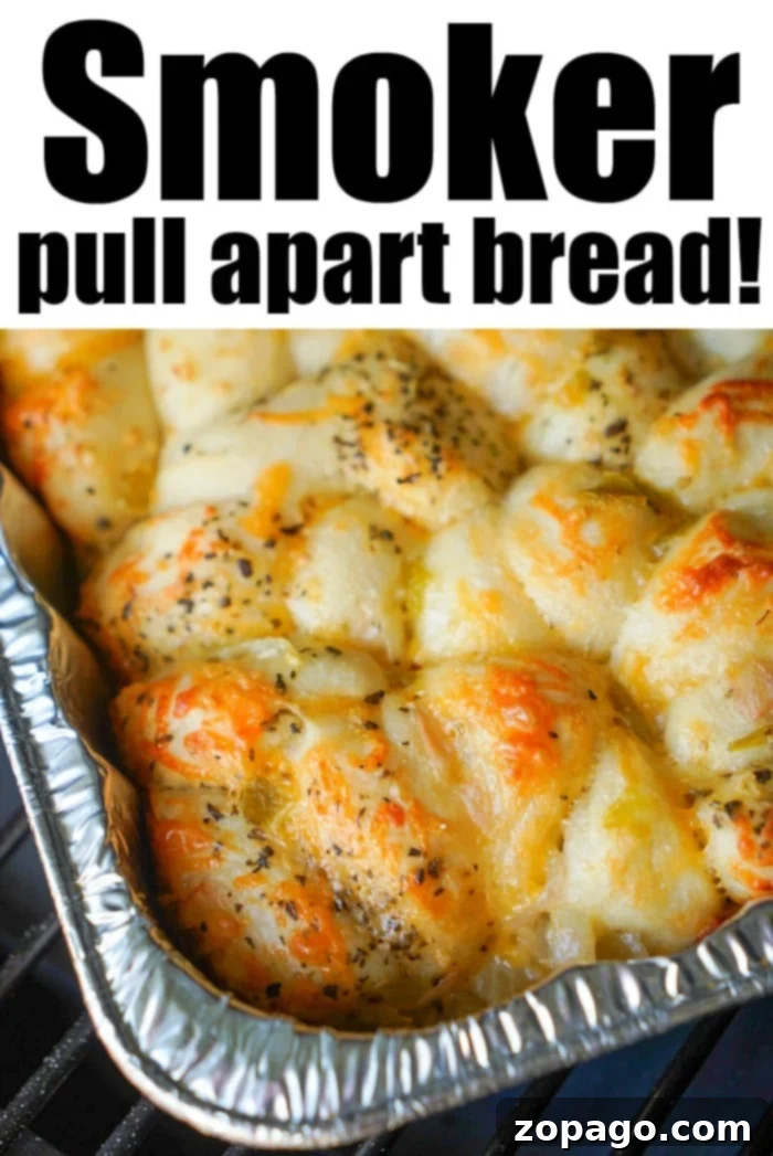 Smoky Traeger Pull-Apart Loaf 10 A rectangular foil tray filled with pull-apart smoked bread, topped with herbs and melted cheese. The bread appears to be cooked on a smoker. Text on the image reads: Smoker pull apart bread!