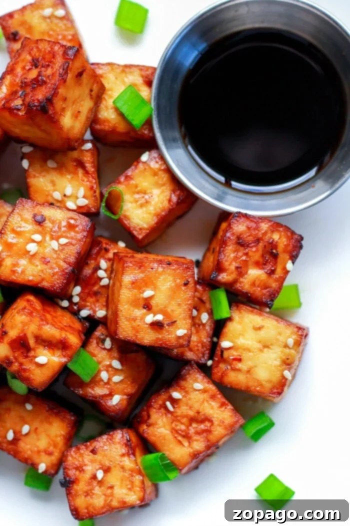 Flavorful Crispy Air Fryer Tofu 5 A serving of golden-brown air fryer tofu, garnished with sesame seeds and green onions, ready to be enjoyed as a snack or meal component.