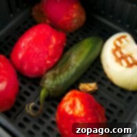 Learn how to roast tomatoes, jalapeños, onions, and garlic cloves effortlessly in an air fryer basket for a delicious homemade salsa.