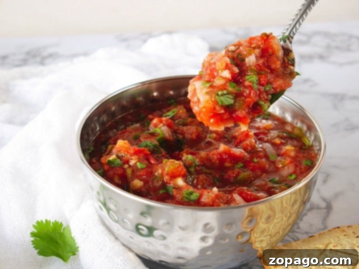 Air Fryer Roasted Tomatoes 6 A vibrant bowl of homemade salsa, made with air fryer roasted tomatoes, showcasing its chunky texture and the freshness of its ingredients like cilantro and onion.