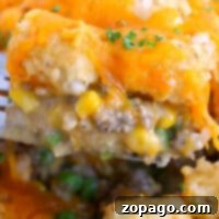 Close-up of a potato tot casserole with ground beef, corn, peas, and gooey melted cheese on top.