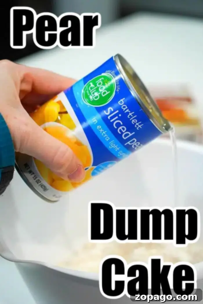 Effortless 3 Ingredient Dump Cake 3 A hand is pouring a can of sliced pears in extra light syrup into a white mixing bowl. The can has a blue label with an image of pears.