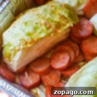 In a foil tray, smoked sausage slices pair perfectly with cabbage wedges, ready for cooking.