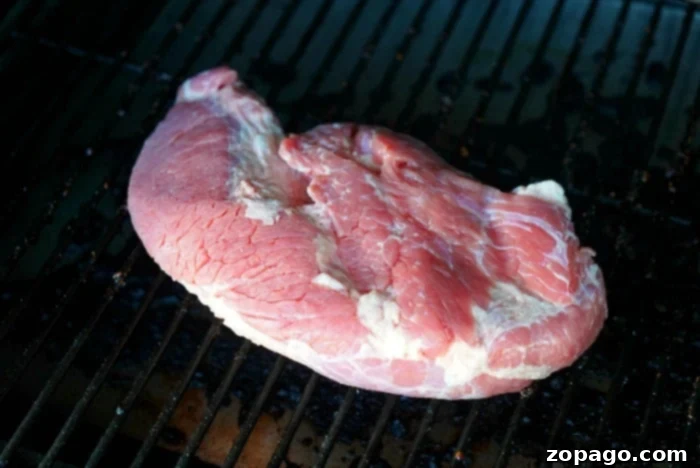 Slow Smoked Corned Beef 5 A juicy corned beef brisket sizzling on the grates of a Traeger smoker, developing a delicious crust.