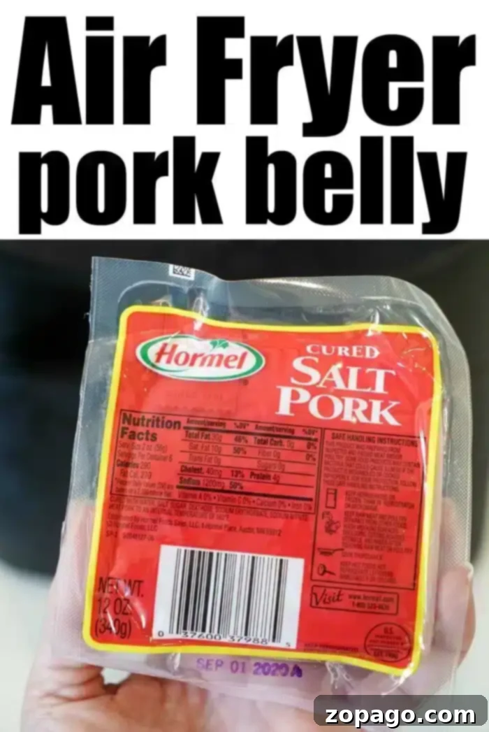 Crispy Air Fryer Pork Belly 4 A hand holds a pack of Hormel cured salt pork, perfect for making air fryer pork belly. The packaging displays nutritional facts and a barcode. The text above the image reads "Air Fryer pork belly" in bold black letters. The expiration date on the package is September 01, 2023.
