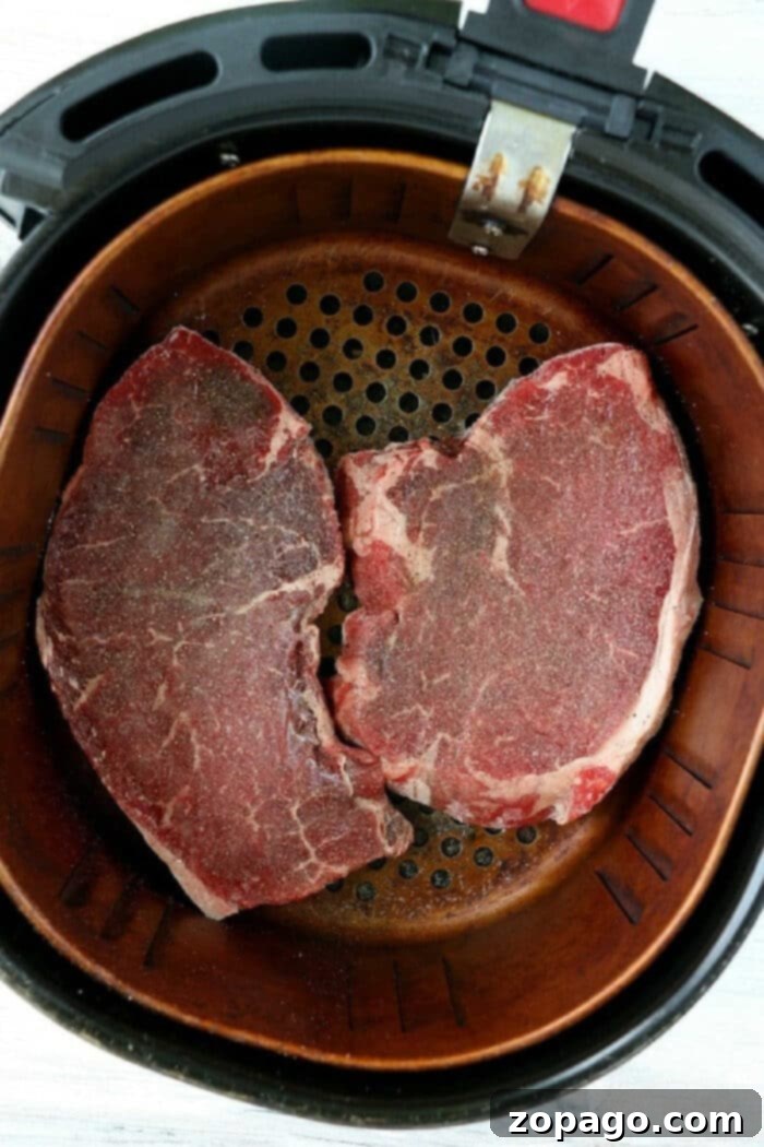 Air Fryer Steak Straight From Freezer 4 Two air-fried frozen steaks, sliced to reveal a perfect medium-rare doneness, garnished with fresh herbs on a cutting board.