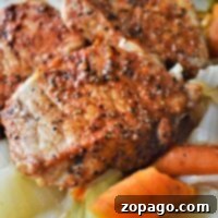 Pan-seared pork chops, starting from frozen, are perfectly cooked in an Instant Pot with spices and served alongside roasted carrots and cabbage on a plate.