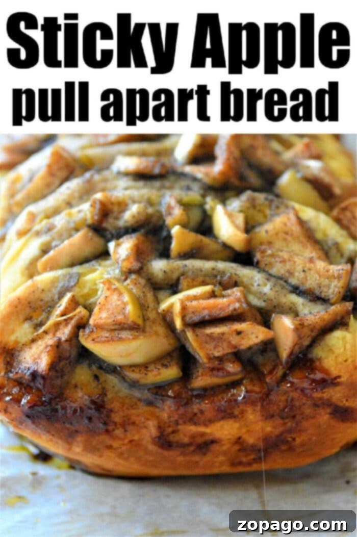 Sweet Cinnamon Pull-Apart Delight 5 A beautiful loaf of sticky cinnamon pull apart bread, topped with baked apples and cinnamon, presented warm on parchment paper.