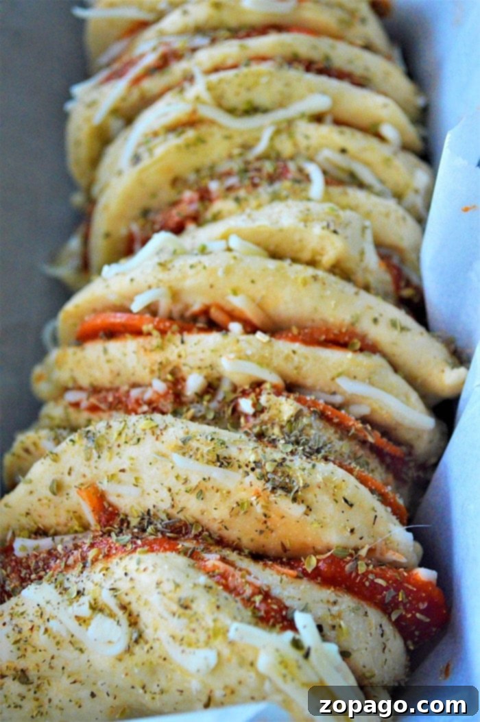 Pizza Monkey Bread 4 Arrangement of pull apart pizza bread layers in a loaf pan, ready for baking, showcasing the pepperoni and cheese filling.